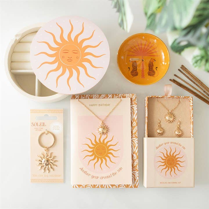 Sun-themed jewelry set with necklaces and pendants on a white surface.