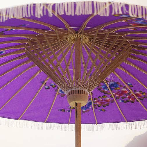 Purple parasol with decorative patterns and white fringe on a white background
