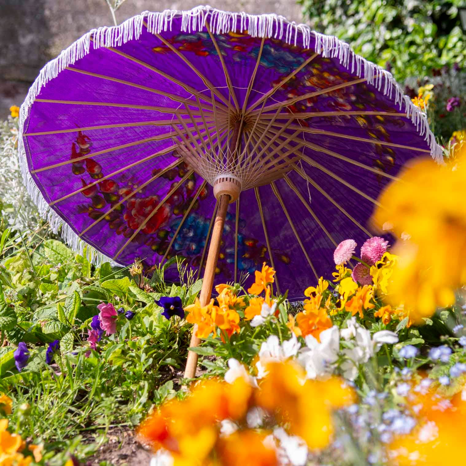 Purple decorative umbrella with floral patterns in a garden setting