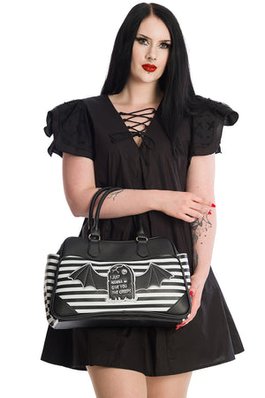 Woman holding a black and white striped handbag with bat designs on a white background