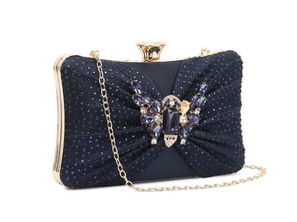 Navy blue clutch bag with butterfly embellishment and gold chain strap on a white background