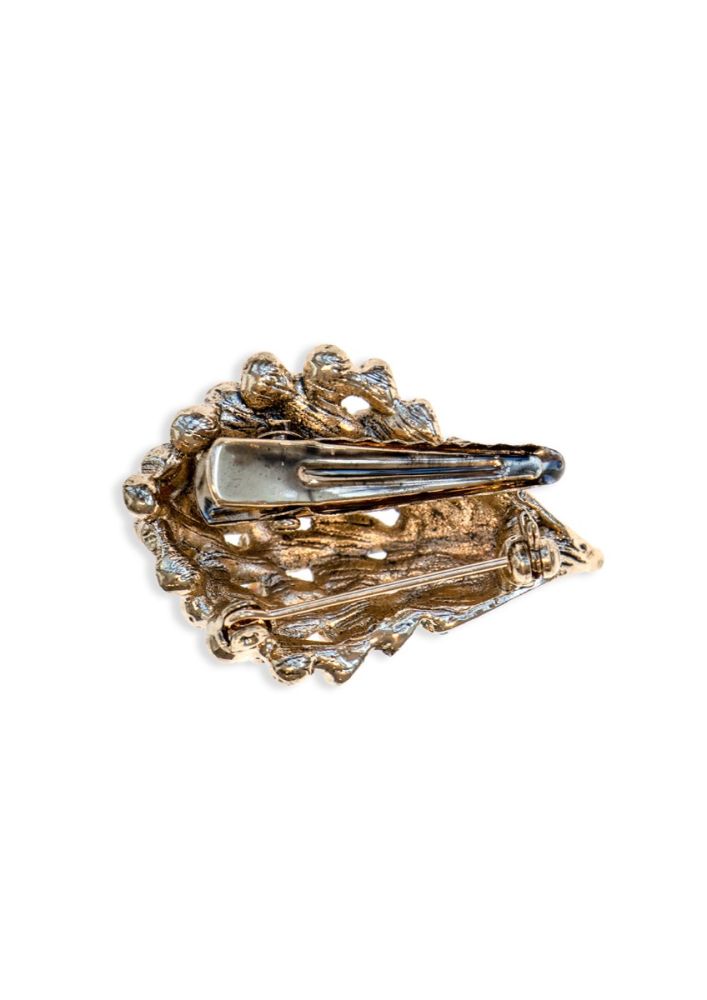 Gold brooch with intricate design and gemstones on a white background