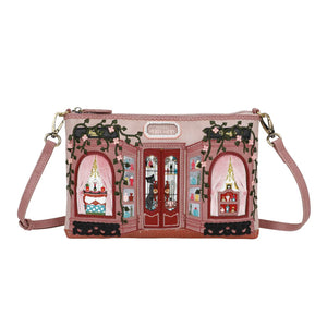 Pink crossbody bag with decorative design on a white background