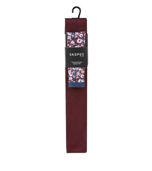 Packaged burgundy tie with floral pattern on packaging against a white background